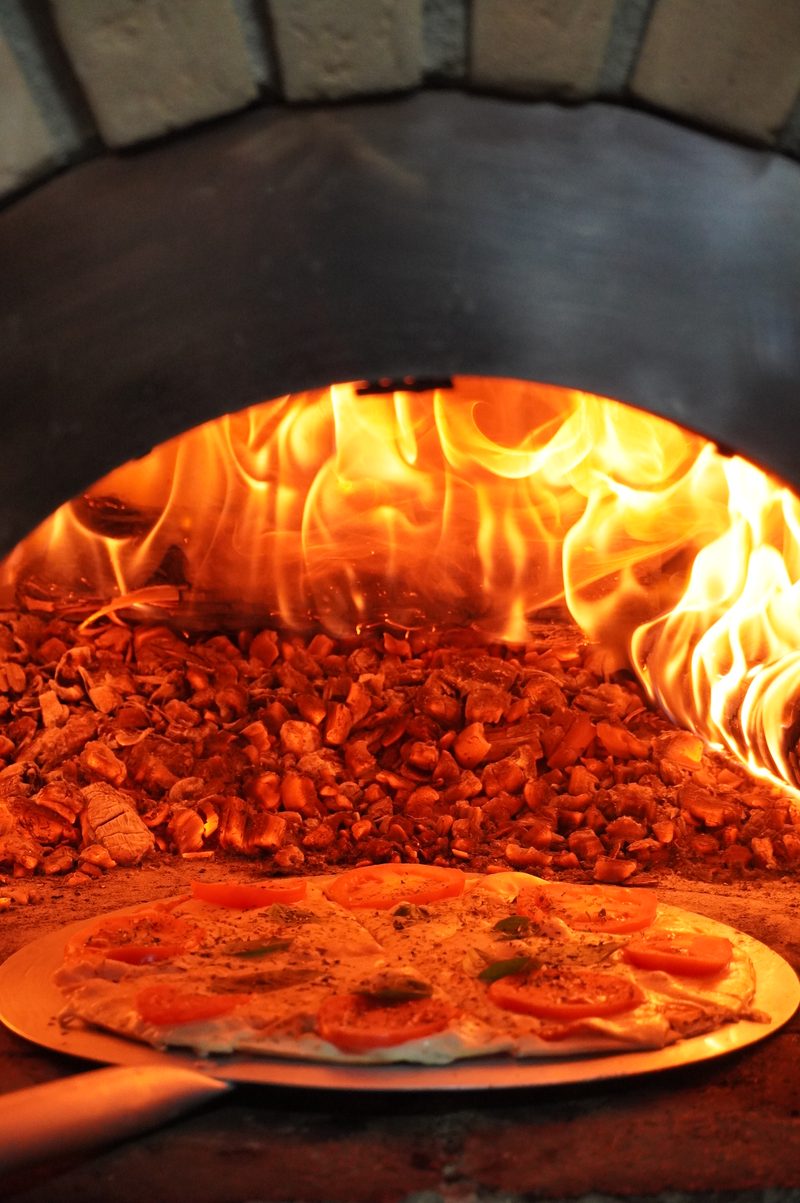 Pizza marguerita entrando no forno em chamas